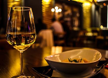 A plated dish and glass of wine in a warmly lit dining room